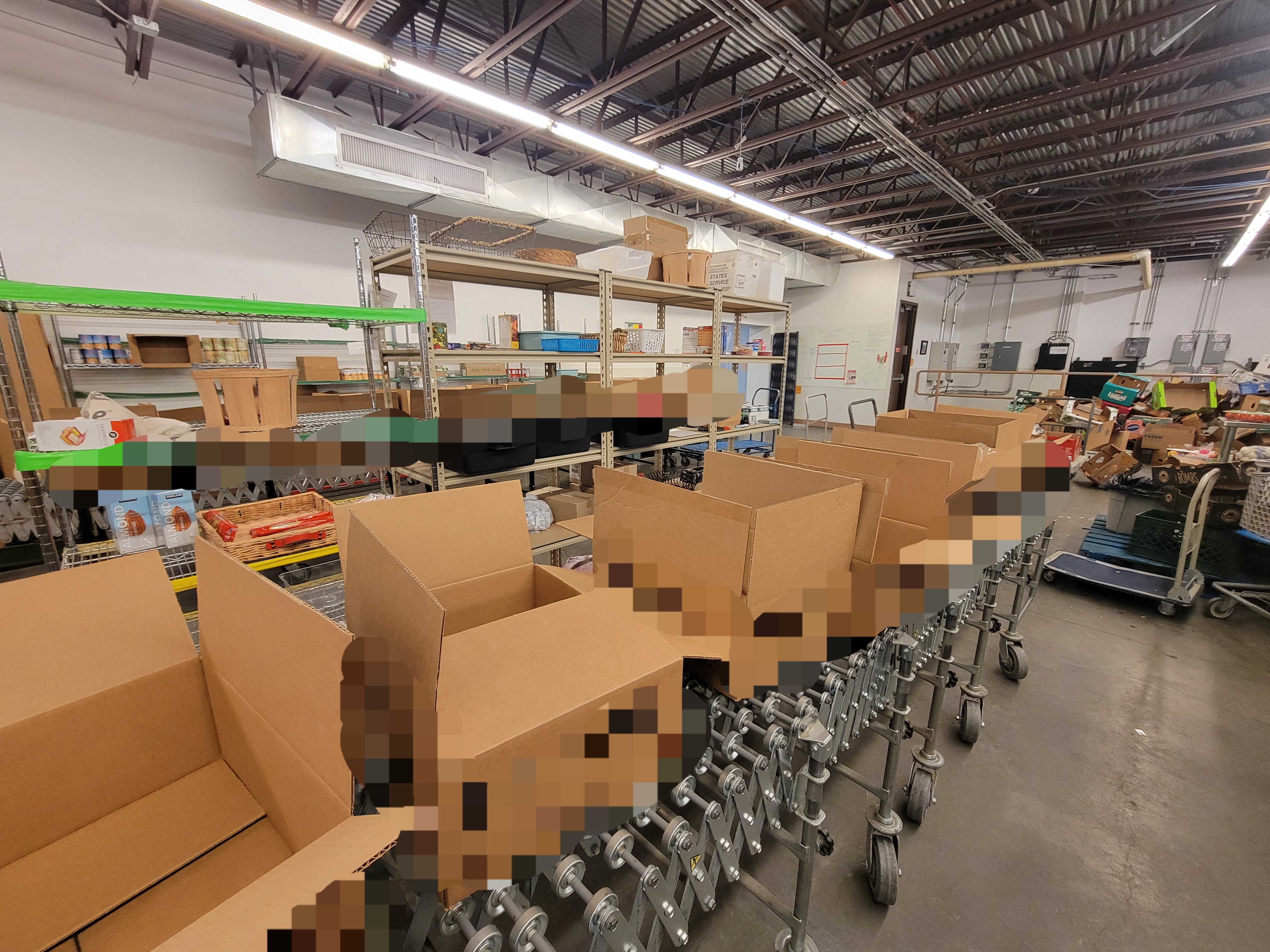 Open boxes on conveyor belt with shelves and another box filled conveyor belt behind it